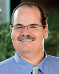 A man with glasses and mustache wearing blue shirt.